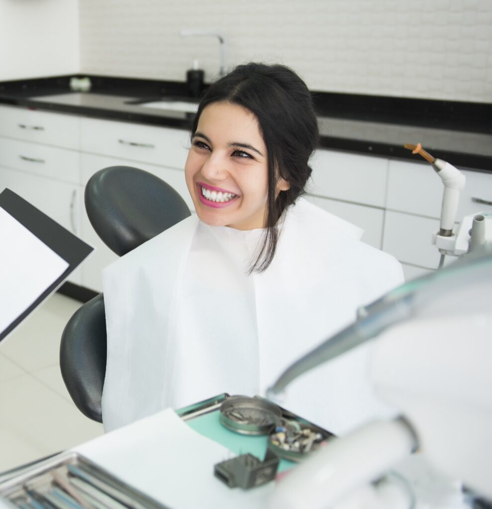 Young woman grinning at her dentist while in a dental bid at her dental check up
