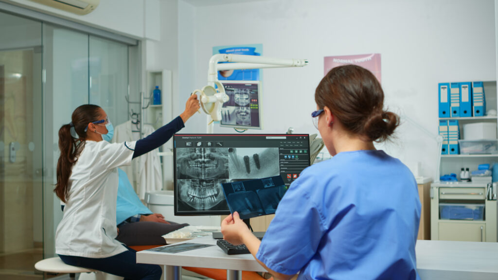 Stomatologist Nurse Comparing Radiographics Looking At Computer