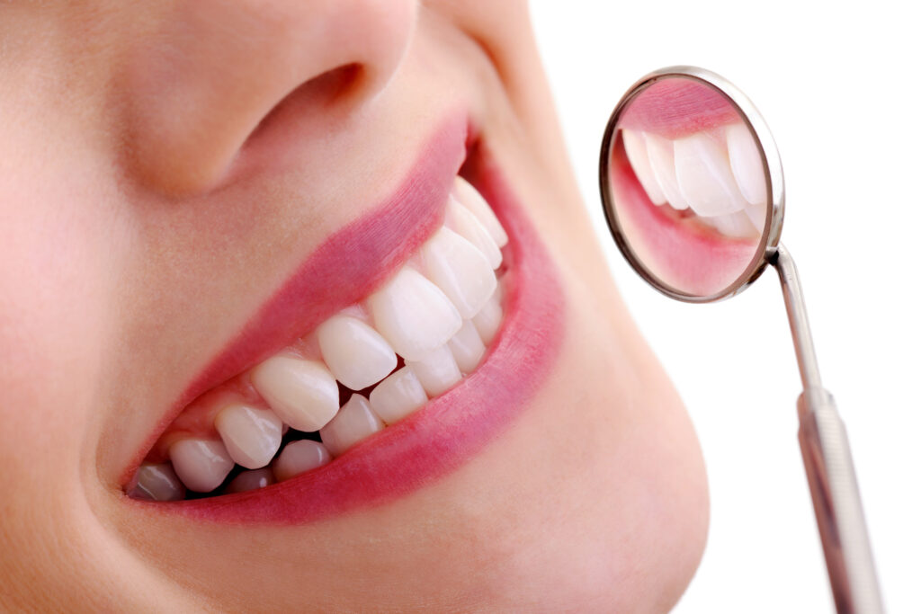 Close up of the smile of a woman being examined by a dental mirror